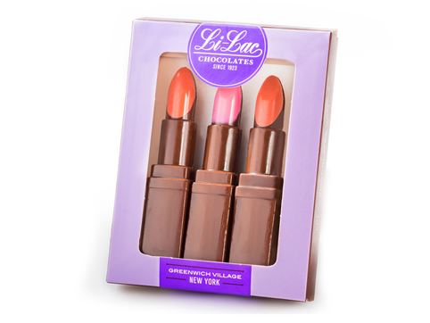 A purple branded card stock box holds three molded chocolate lipsticks. Each lipstick has a different color chocolate.
