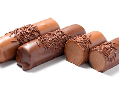 Little cylindrical rolls of chocolate mousse ganache are lined up together. They are covered in milk chocolate and coated with tiny chocolate sprinkles. One log is cut in half revealing the soft mousse interior.