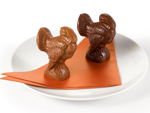 A three inch tall chocolate molded turkey stands with a fanned out tail.