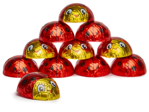 Chocolates wrapped in red and gold foil that have a decoration that makes them look like little round smiling ladybugs.