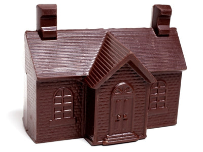 A chocoate molded three-dimensional schoolhouse building with pitched roof and two chimneys.