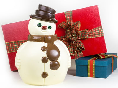 A large round white chocolate snowman has a milk chocolate scarf and a dark chocolate hat