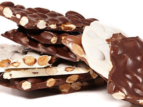 Thin sheets of almond bark are shown in milk, dark or white chocolate. The sheets are broken into pieces, exposing the toasted almonds inside. 