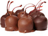 Stemmed cherries, enrobed in milk and dark chocolate sit together.