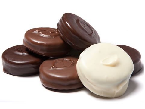 Milk, dark and white chocolate covered Oreo cookies are stacked together.