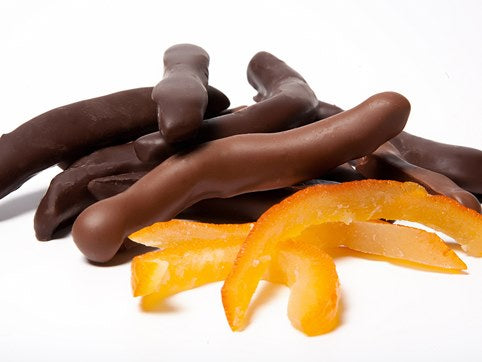 Pieces of candied, glace orange peel, enrobed in dark or milk chocolate sit together.