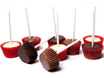 Milk, dark and white chocolate kiddie pops are sitting together. The chocolate was poured into mini paper cups with a lollipop stick inserted in the middle.