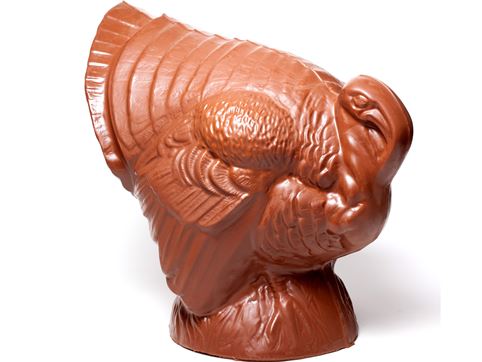 A giant molded chocolate Turkey stands with it's tail fanned out.