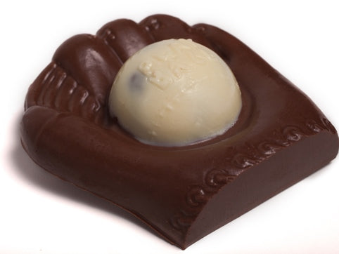 A white chocolate baseball sits in a dark chocolate molded glove.