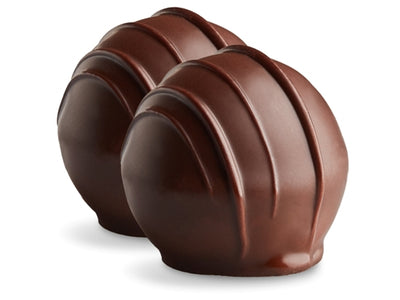 Two amaretto truffles sit side by side. They are enrobed in dark chocolate with dark chocolate drizzles in straight lines on top. 
