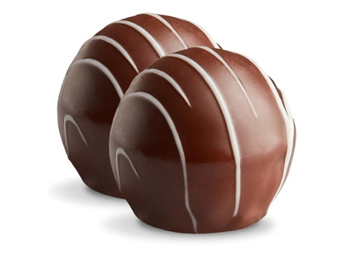 Two caramel truffles sit side by side. They are enrobed in dark chocolate with white chocolate drizzles in straight lines on top. 