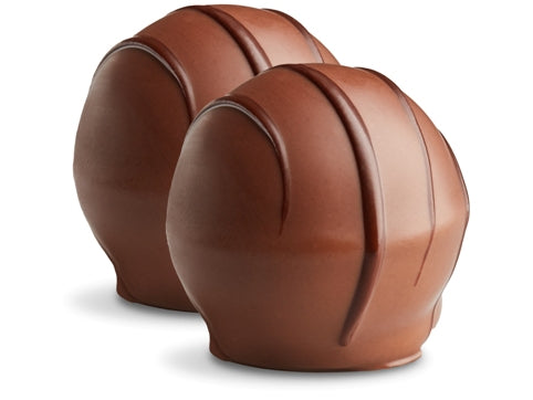 Two champagne truffles sit side by side. They are enrobed in milk chocolate with dark chocolate drizzles in straight lines on top. 