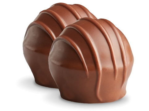 Two raspberry truffles sit side by side. They are enrobed in milk chocolate with milk chocolate drizzles in straight lines on top. 