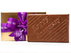 A large rectangular chocolate abr has the words "Happy Anniversary" molded onto the front. It comes in a gold gift box tied with a purple ribbon.