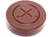 Molded Chocolate hocky puck has crossed hockey stick logo in the middle.