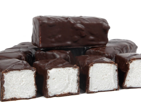 Thick bars of marshmallow enrobed in dark chocolate are lined up together. The bars are cut so that you can see the soft white marshmallow inside.
