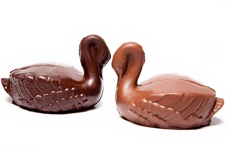 Molded chocolate swans have their heads tucked in making an arched neck. There are feather details as well.
