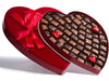Sixty-three assorted chocolates sit inside a very large heart shaped box. 