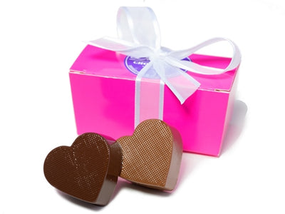 A little pink rectangular box holds two molded chocolate hearts, one milk and one dark.