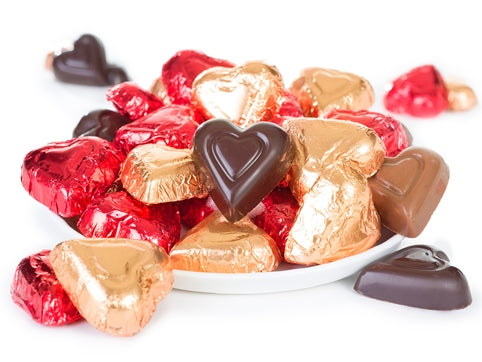 Molded chocolate hearts are wrapped in foil. Milk chocolate are wrapped in red foil and dark chocolate are wrapped in bronze foil.