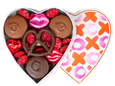 Chocolate covered oreos, pretzel, nonpareils and foil wrapped molded foil wrapped lips sit inside a fun X and O patterned heart shaped box. 